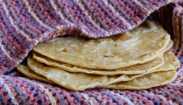 Very close up view of four tortillas partially wrapped in woven cloth.