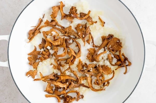 Rehydrated chanterelle mushrooms sauteing in a skillet with garlic and onions.