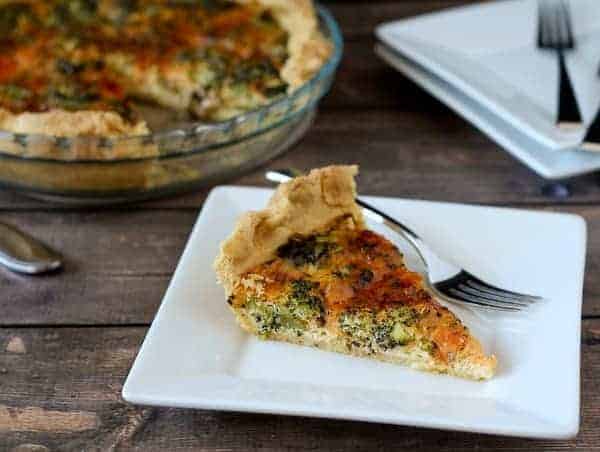 Slice of roasted broccoli quiche on a square white plate.