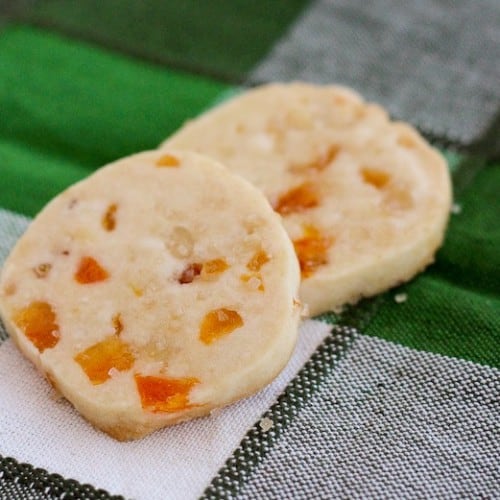 Closeup of two stacked shortbread cookies on green plaid cloth.