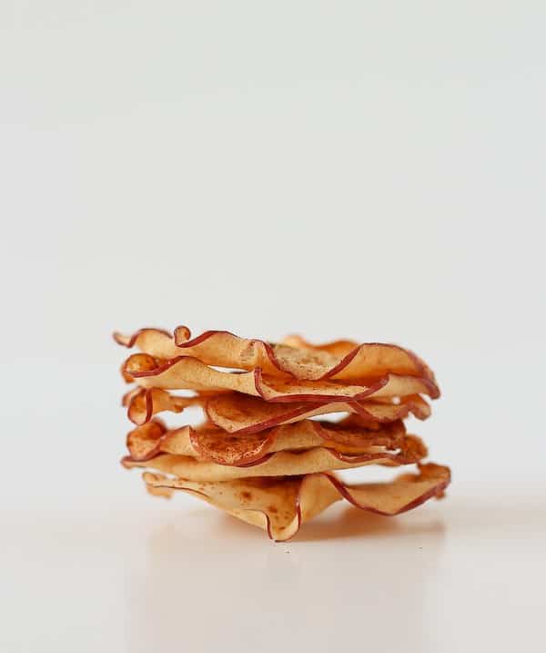 Close up front view of stacked apple chips, on white background.