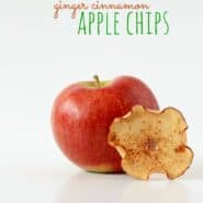 One apple chip, propped on a red apple, with text overlay "Ginger Cinnamon Apple Chips."