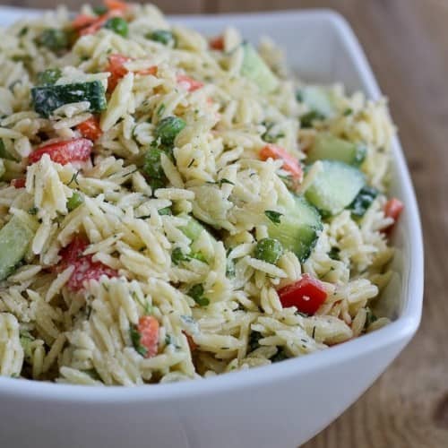 Close up view of an orzo pasta salad with dill dressing in a white bowl