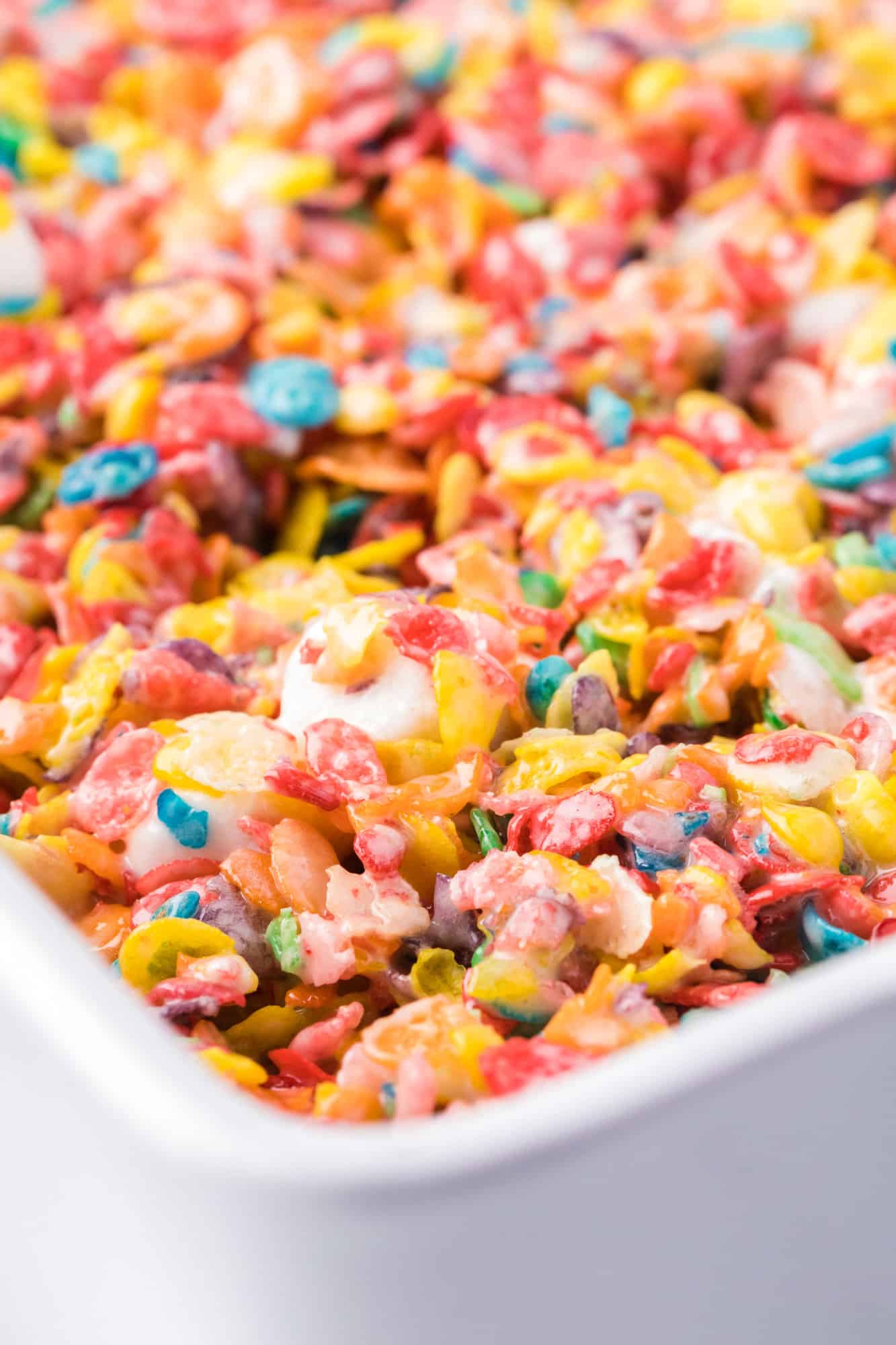 Close up of Fruity Pebbles treats in a parchment-lined baking pan.