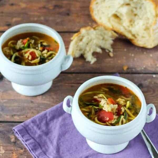 Turkey soup in small white pedestal bowls with rustic bread.