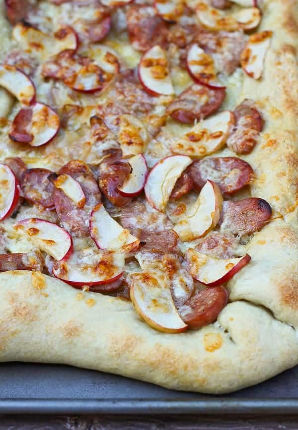 Pizza topped with sausage, apples, and cheese.