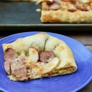 Slice of pizza revealing macaroni and cheese stuffed in the crust.