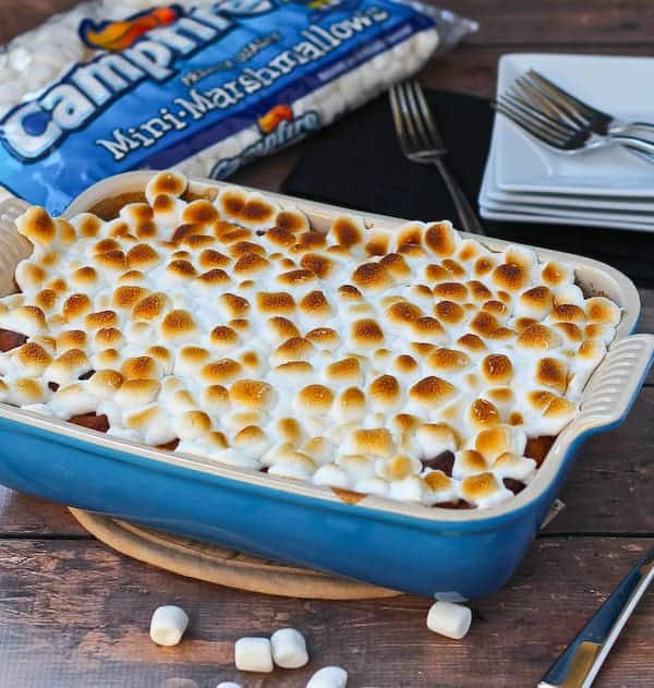 Front view of bread pudding with marshmallows scattered in front and partial image of a bag of Campfire marshmallows in background.
