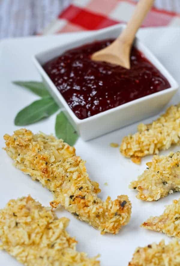Baked tenders on a plate with a square dish of cranberry barbecue sauce.