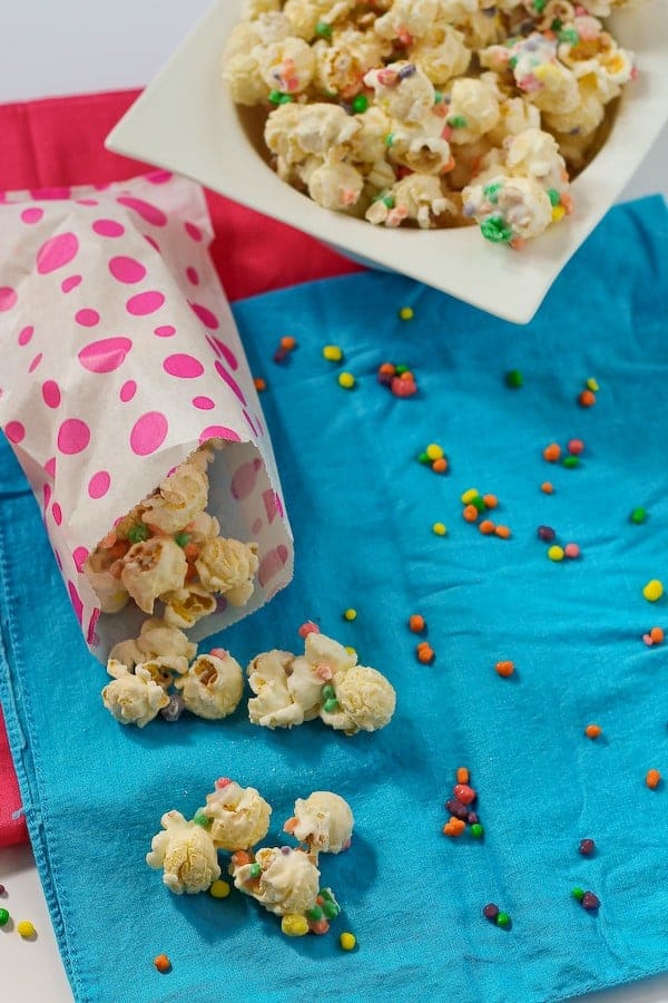 Pink dotted treat bag with nerds popcorn, square white bowl with popcorn in background.