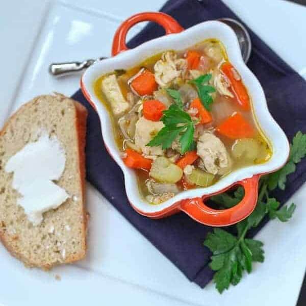 Overhead of soup in decorative orange bowl with handles, garnished with sprig of parsley.