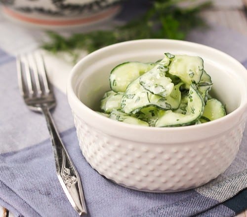 Small white serving bowl with cucumber salad.