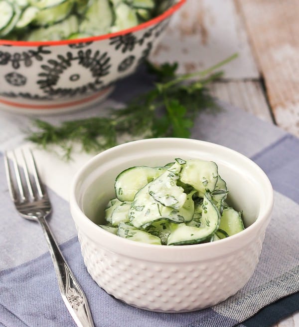 A serving of cucumber salad with fresh dill stems in background.