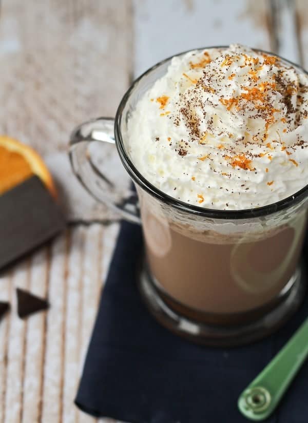 Overhead of hot chocolate garnished with whipped cream, cocoa powder, and orange zest.