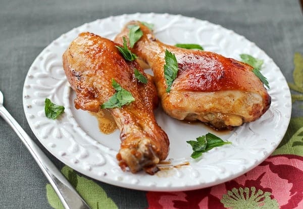 Two drumsticks on white plate garnished with parsley.