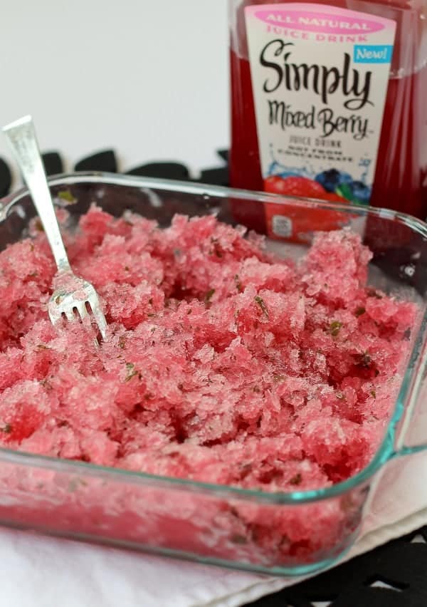 Close up image of granita in clear square baking dish, with fork inserted. A partial image of a Simply Mixed Berry bottle is in the back ground.