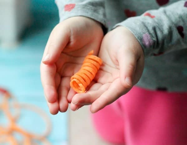 Two hands of a child, cupped together to hold a sweet potato noodle spiral.