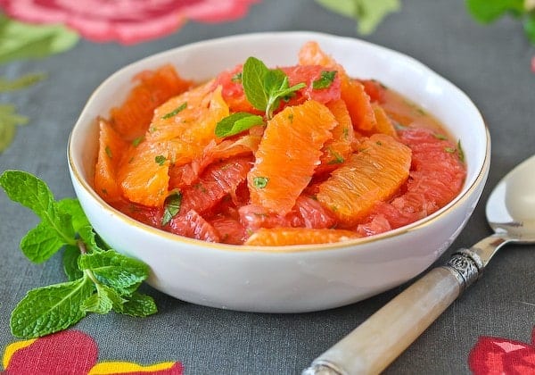 Front view of citrus salad with mint garnish and silver spoon.