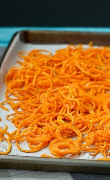 Close up image of a partial sheet pan full of roasted sweet potato noodles.