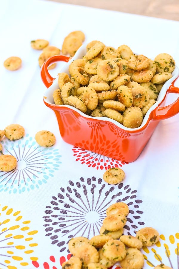 Square orange bowl containing oyster crackers, with lots scattered around dish.
