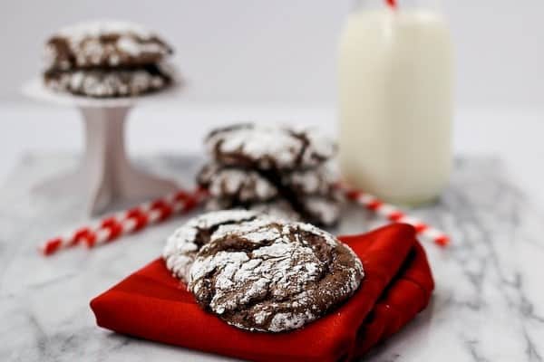 Front view of cookies on napkin, milk bottle and striped straws in background.