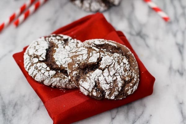 Two cookies on folded red napkin, on white marble surface.