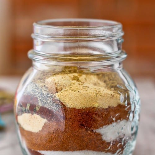 Clear glass jar with layered seasoning ingredients.