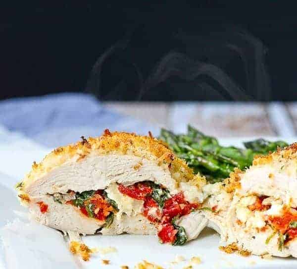 Closeup of stuffed chicken breast, sliced in half., with asparagus in background.