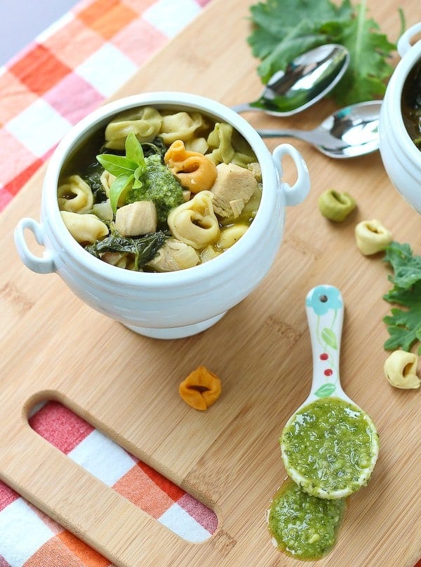 Soup in bowl with spoonful of pesto alongside.