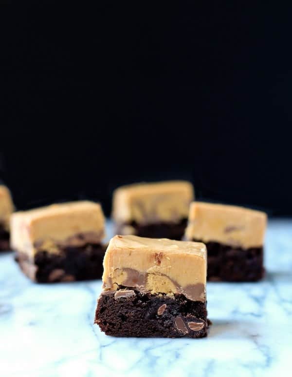 Front view of four cut squares of peanut butter fudge brownies on a marble surface. 