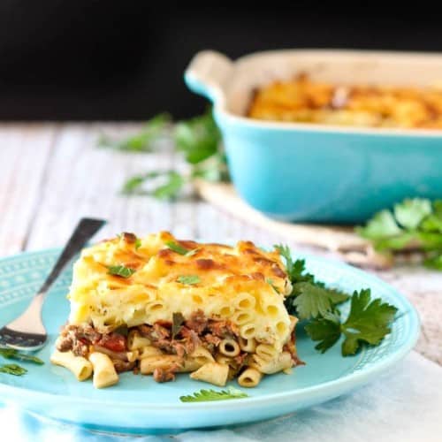 Front view of plated pastitsio with casserole dish in background.