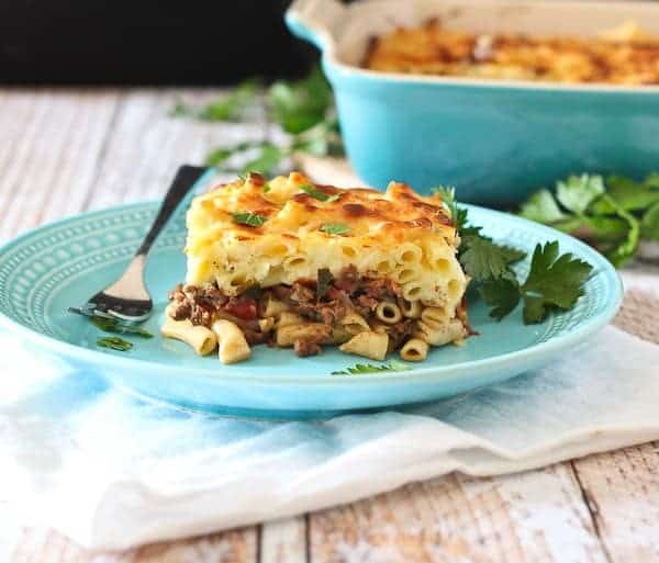 Front view of plated pastitsio with casserole dish in background.