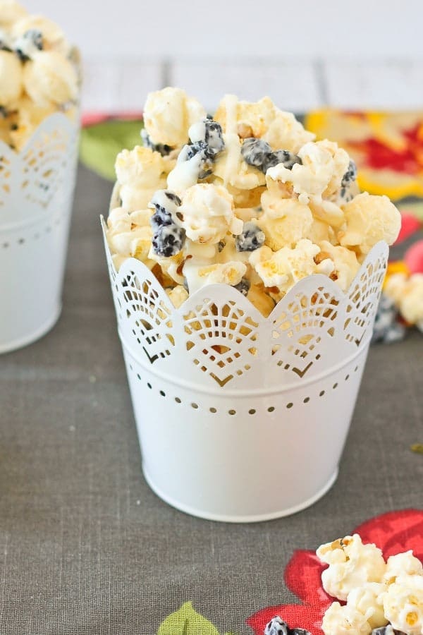 A serving of popcorn in a white lacy decorative cup.