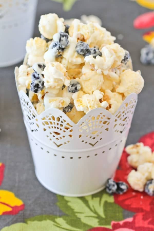 Front view  of popcorn in decorative cup, on floral cloth.