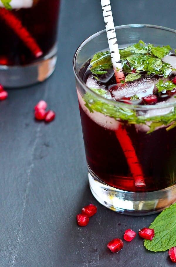 Closeup front view of pomegranate mojito in clear glass tumbler.