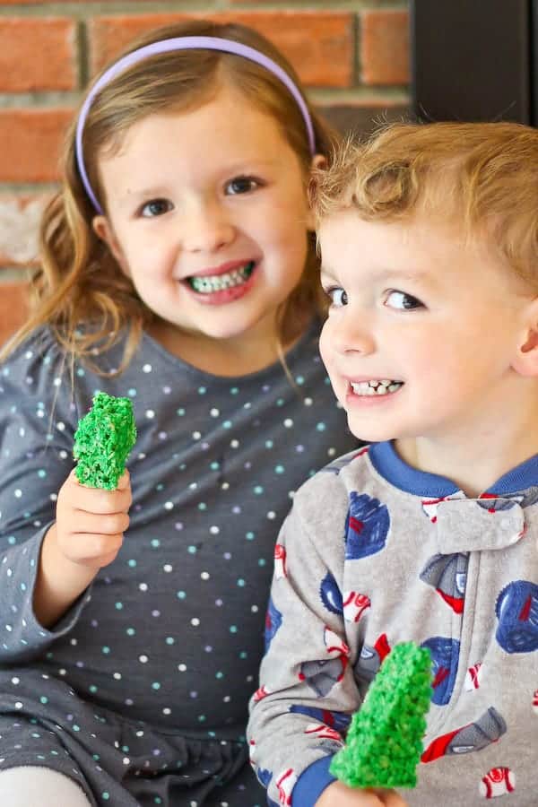 Two young children eating cookies, and showing off their greenish teeth.