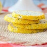 Front view of four poppy seed cookies stacked on burlap cloth.