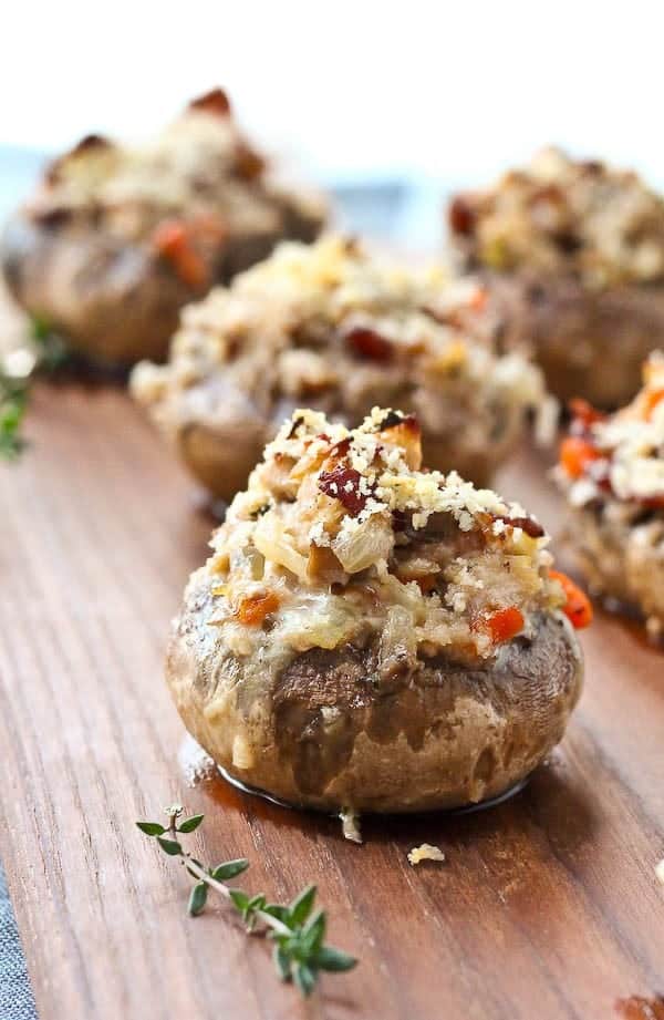 Several stuffed mushrooms on wooden surface, garnished with fresh thyme sprigs.
