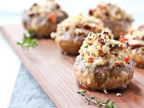 Several stuffed mushrooms on wooden surface, with thyme sprigs.