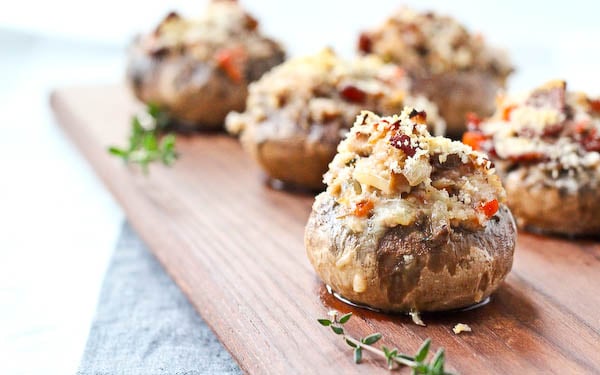 Several stuffed mushrooms on wooden surface, with thyme sprigs.