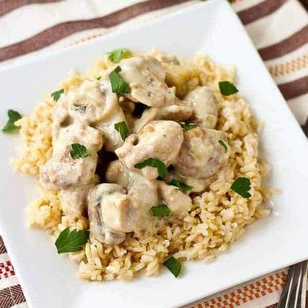Overhead of chicken on rice served on square white plate.
