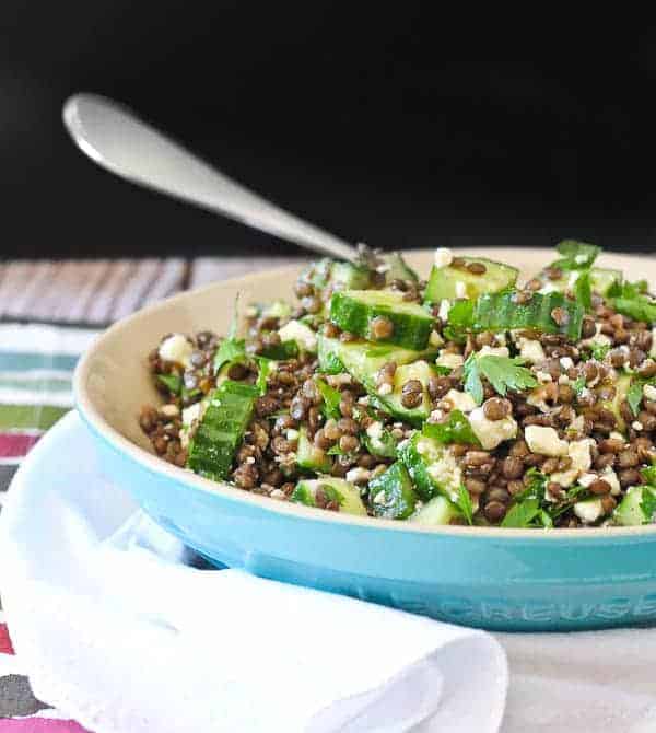 Front view of lentil salad in shallow blue bowl with fork inserted.