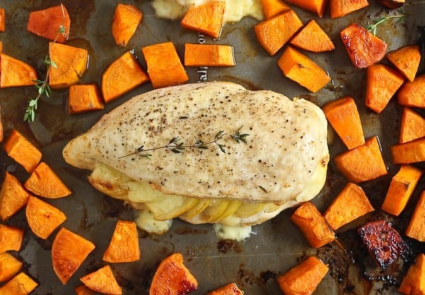 Overhead of a chicken. breast on sheet pan with sweet potatoes.