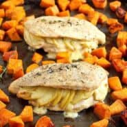 Two stuffed chicken breasts on sheet pan with sweet potatoes.