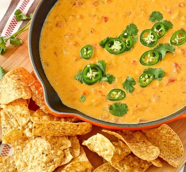 Orange queso dip topped with jalapeño slices. 