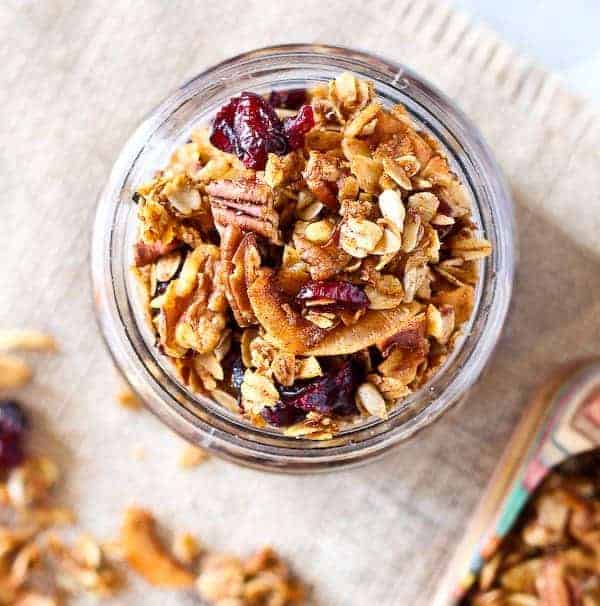 Overhead view of granola in a jar, with cranberries and pecans.