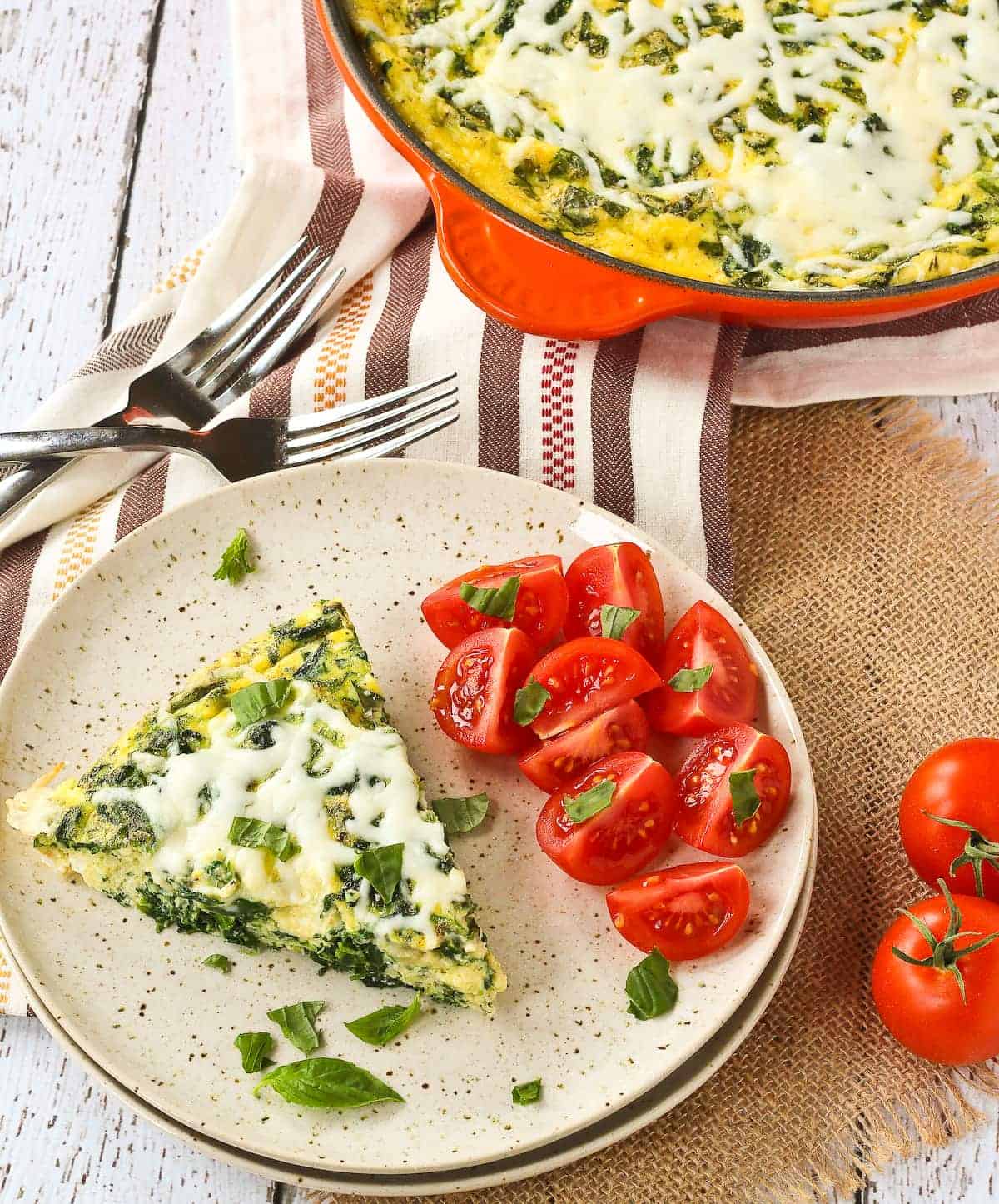 Slice of white pizza frittata on a plate with fresh tomatoes.