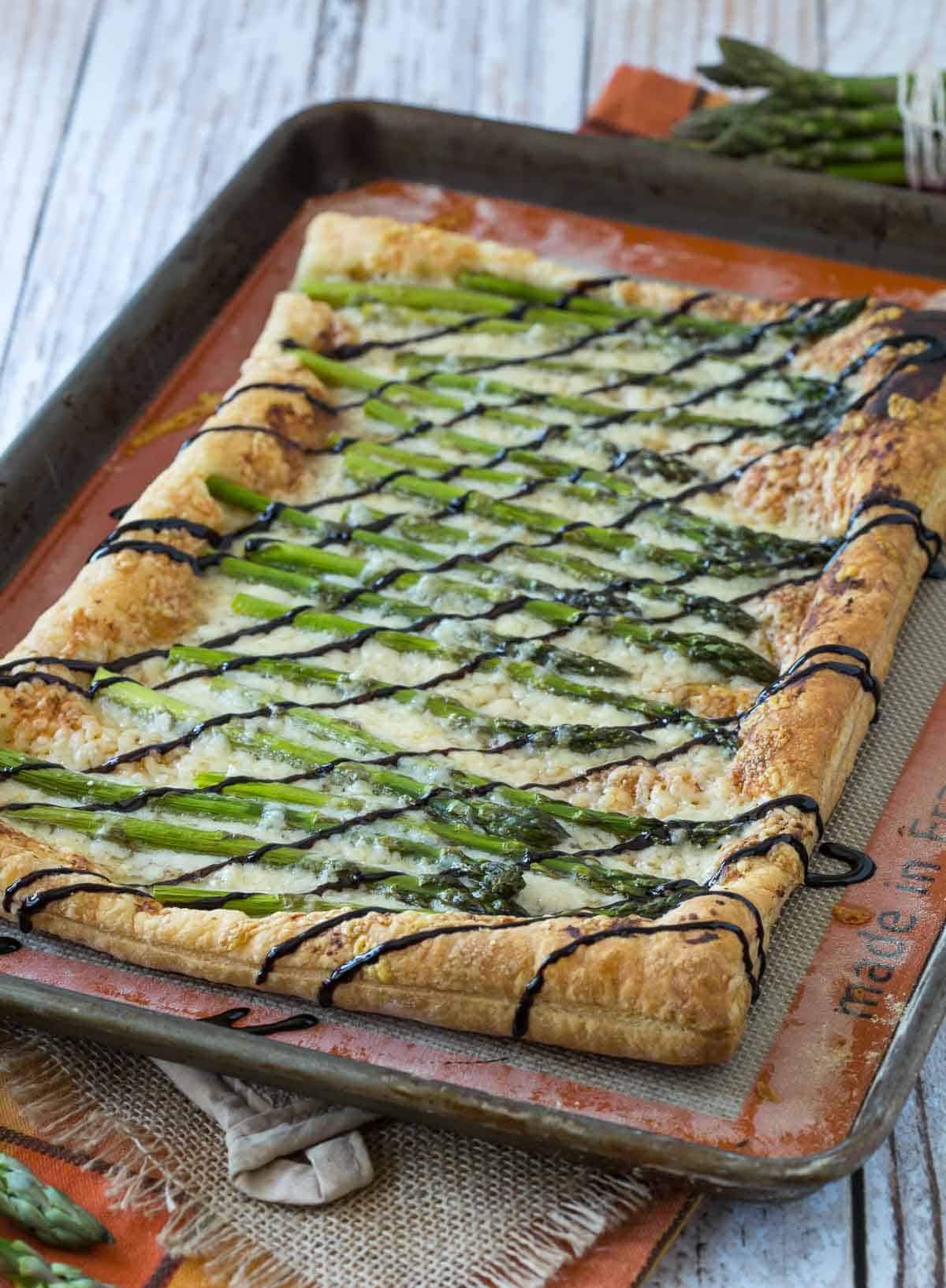 Perfect for spring, this Asparagus Gruyère Tart is a show-stopping addition to any brunch or appetizer table. You won't believe how easy it is to make! Asparagus Gruyère Tart on a sheet pan.