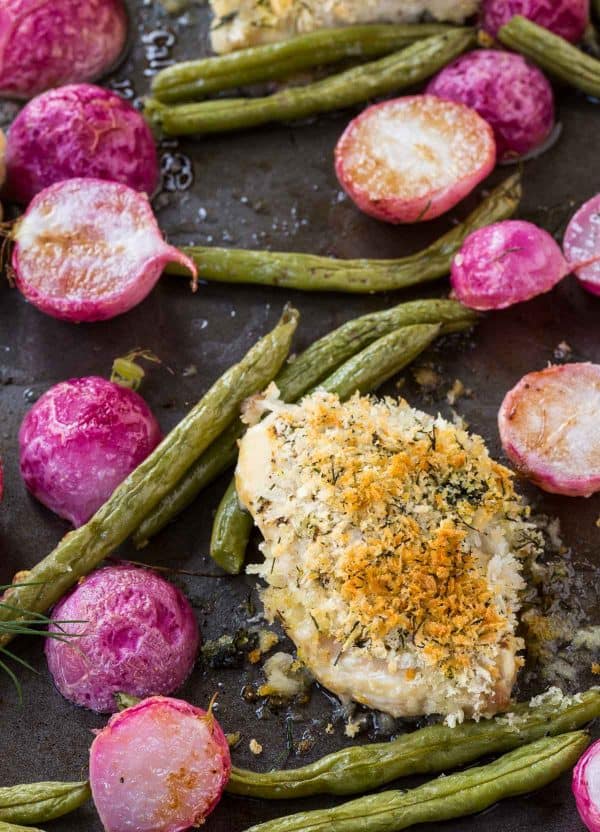 Closeup of roasted chicken, beans, and radishes on sheet pan.
