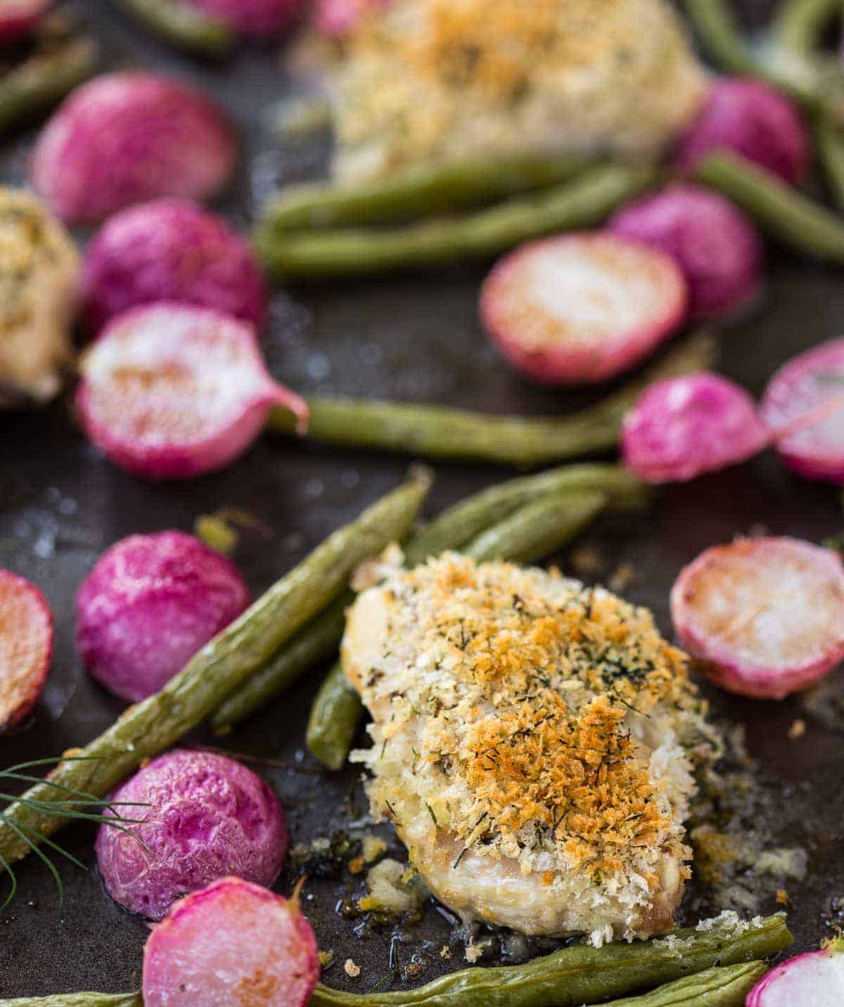 Closeup of roasted chicken and vegetables in sheet pan.